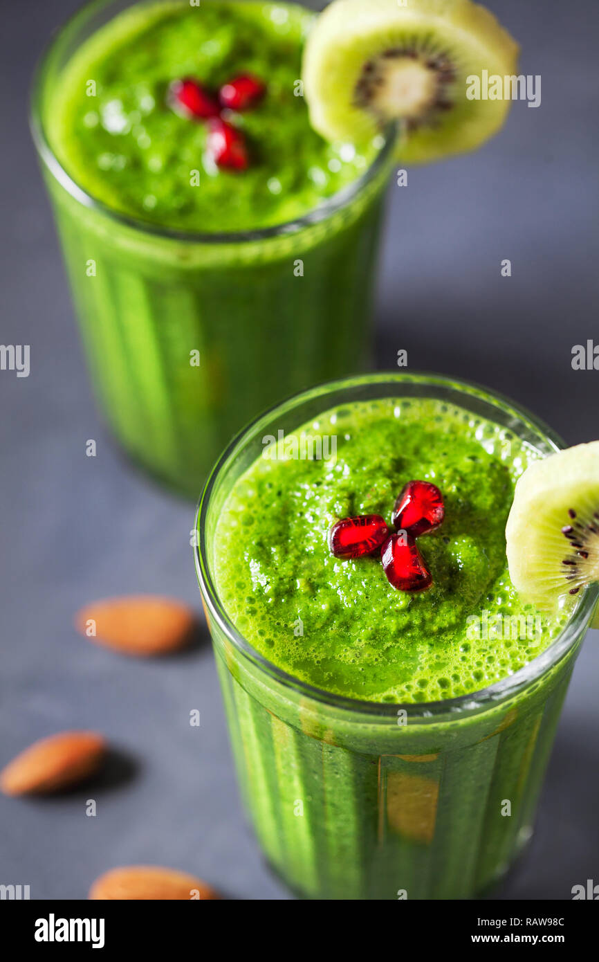Green smoothie with kiwi, apple, spinach, banana and almond milk close up decorated with pomegranate grains Stock Photo