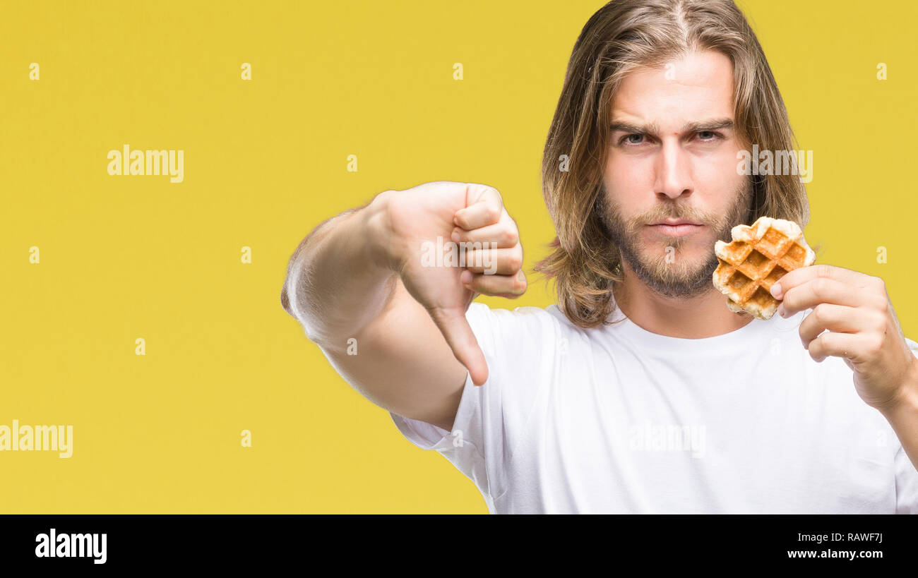 Young handsome man with long hair over isolated background eating ...