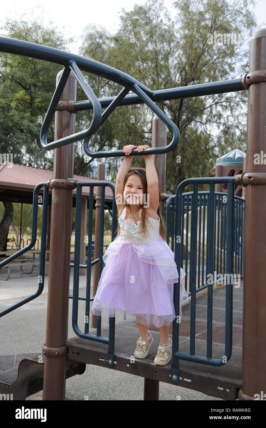 Young Girl Playing on Monkey Bars Playground in a Princess Dress Stock