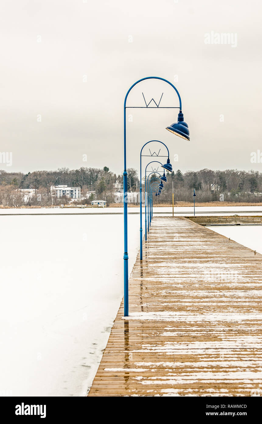 Blue lamp posts with a curve illuminating a dock on a wintry day Stock