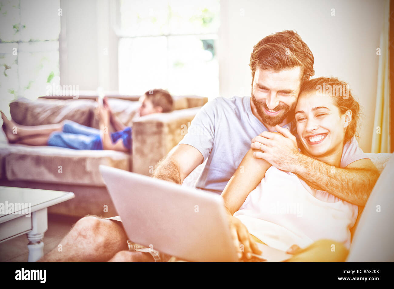 Happy couple sitting on sofa and using laptop Stock Photo