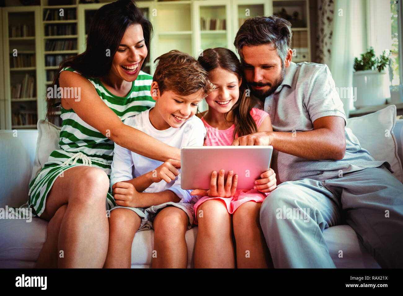 Parents with their children sitting on sofa and using digital tablet Stock Photo