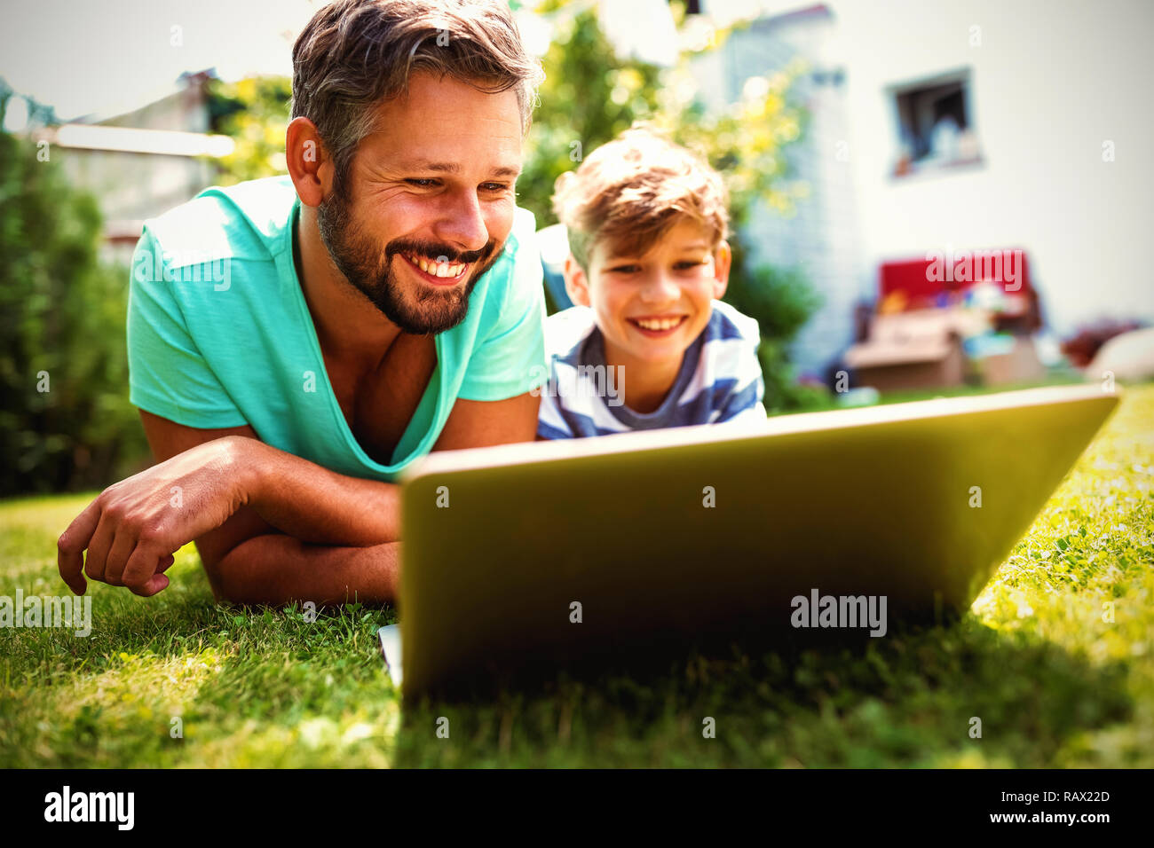 Father and son using laptop in garden Stock Photo