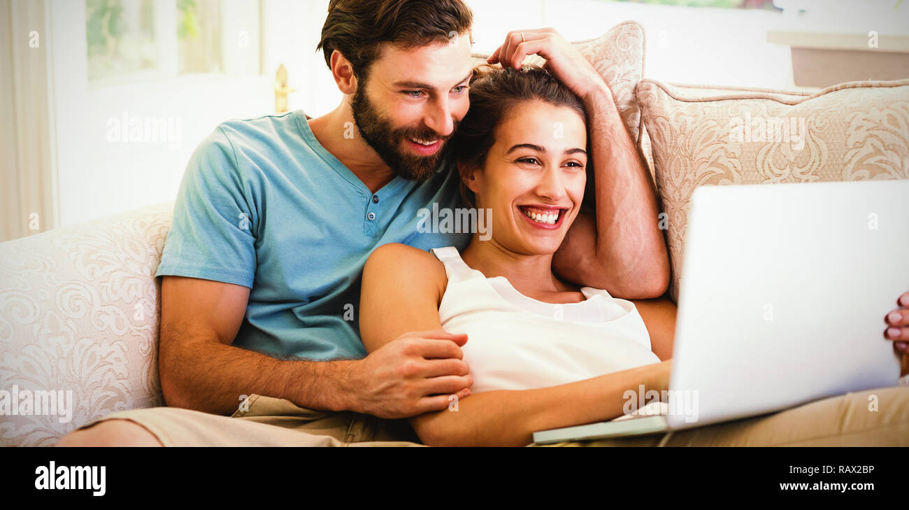 Couple sitting on sofa and using laptop Stock Photo