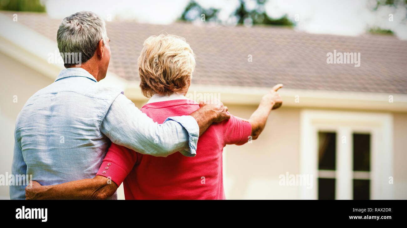 Senior couple looking at house while standing ih yard Stock Photo