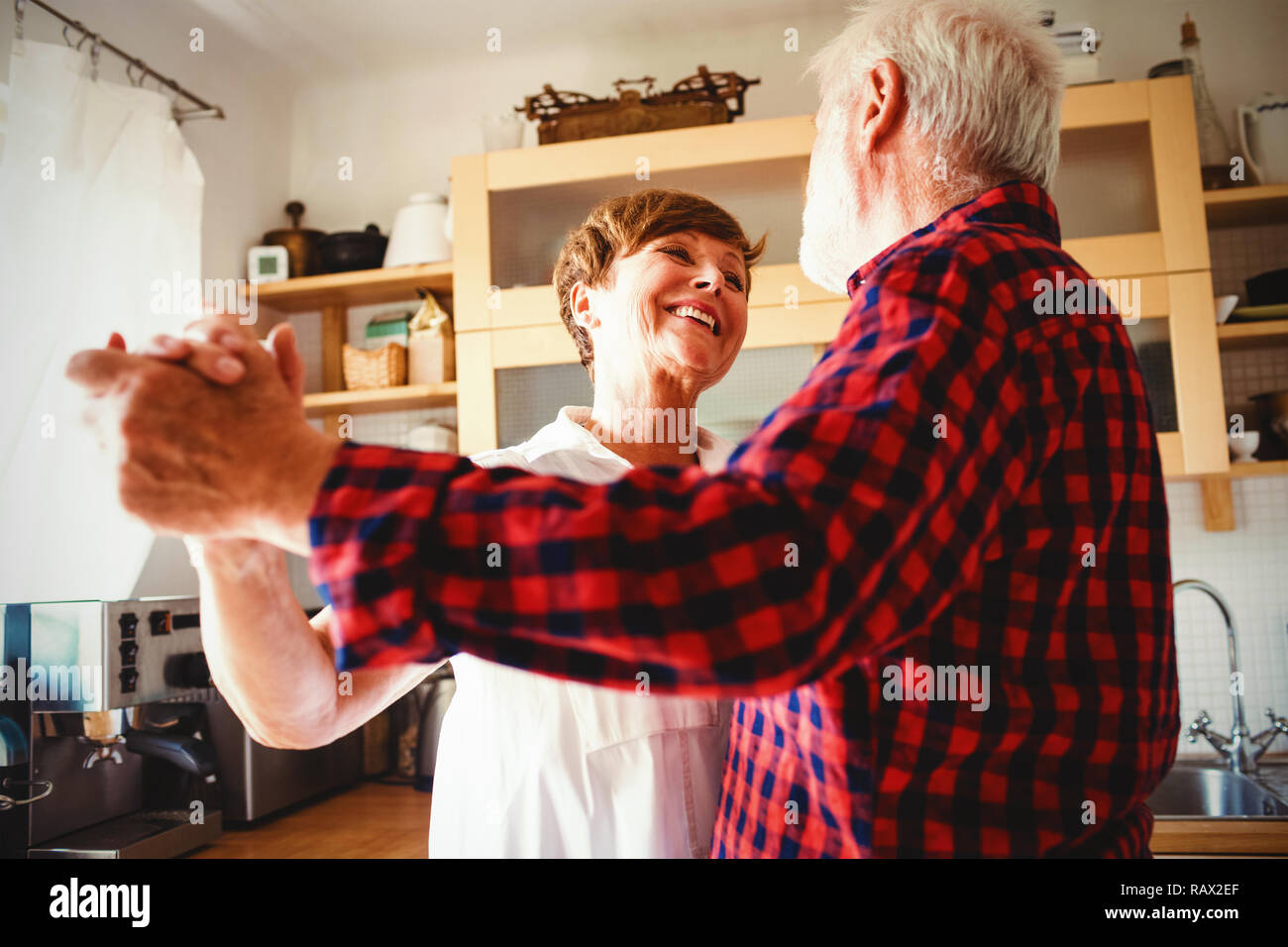 Senior couple dancing together in kitchen Stock Photo