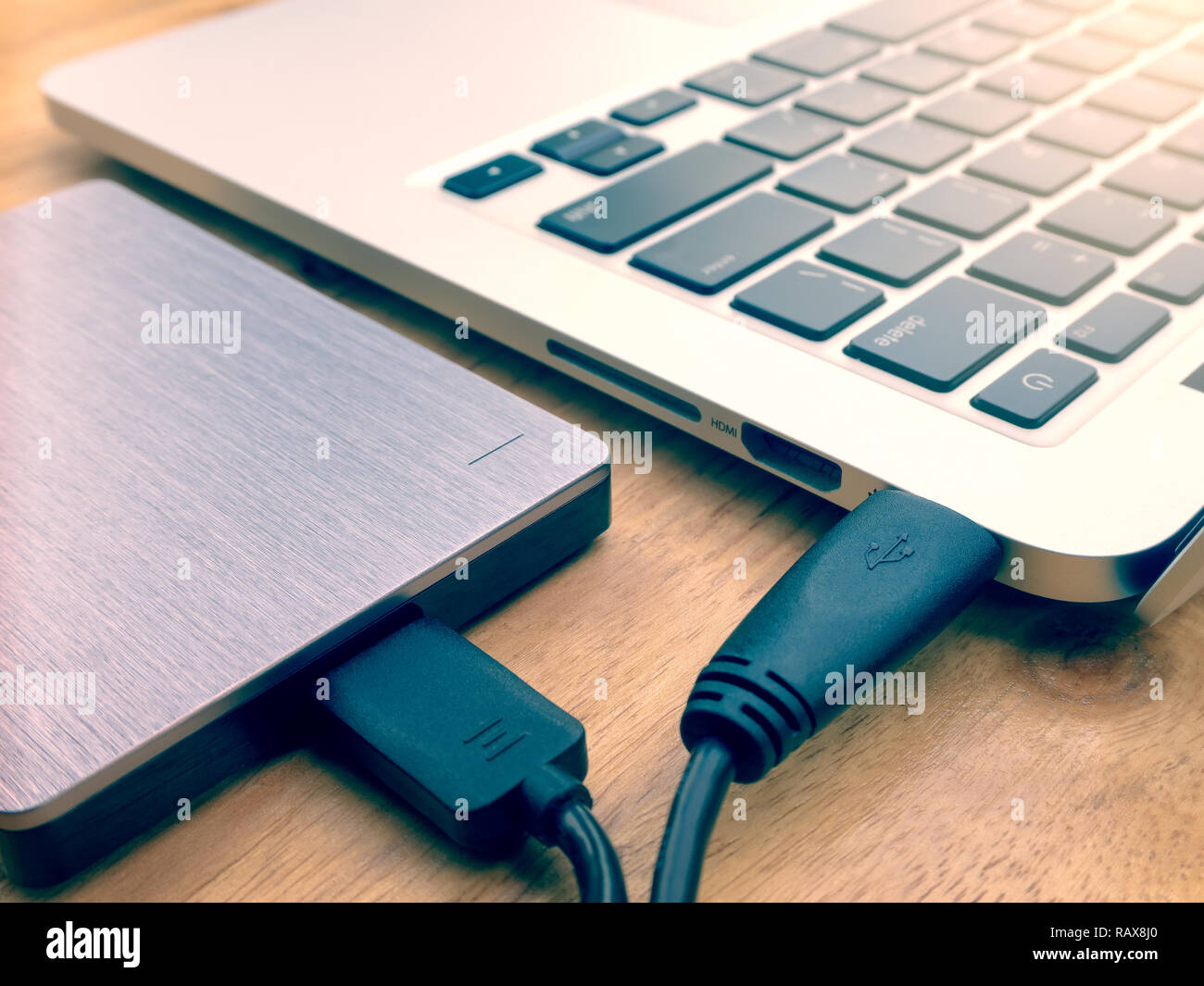 External or portable hard drive (HDD) connected to laptop computer for  transfer or backup data on wooden texture office desktop Stock Photo - Alamy