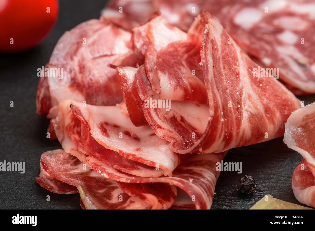 antipasto with sliced salami, cheeses, prosciutto, ham, tomato on black slate background Stock Photo