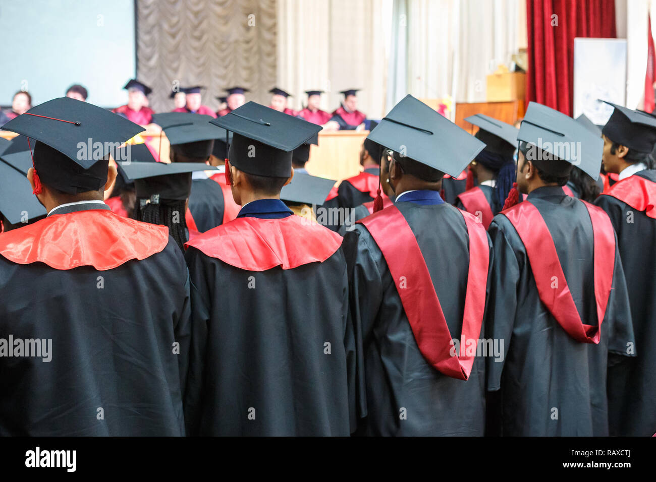 Foreign medical students in square academic graduation caps and black raincoats during commencement Stock Photo