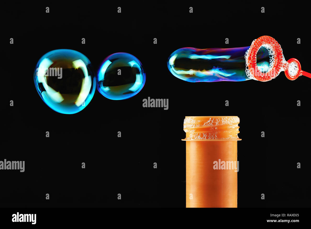 Colored Soap bubbles and orange blower on a black background Stock Photo