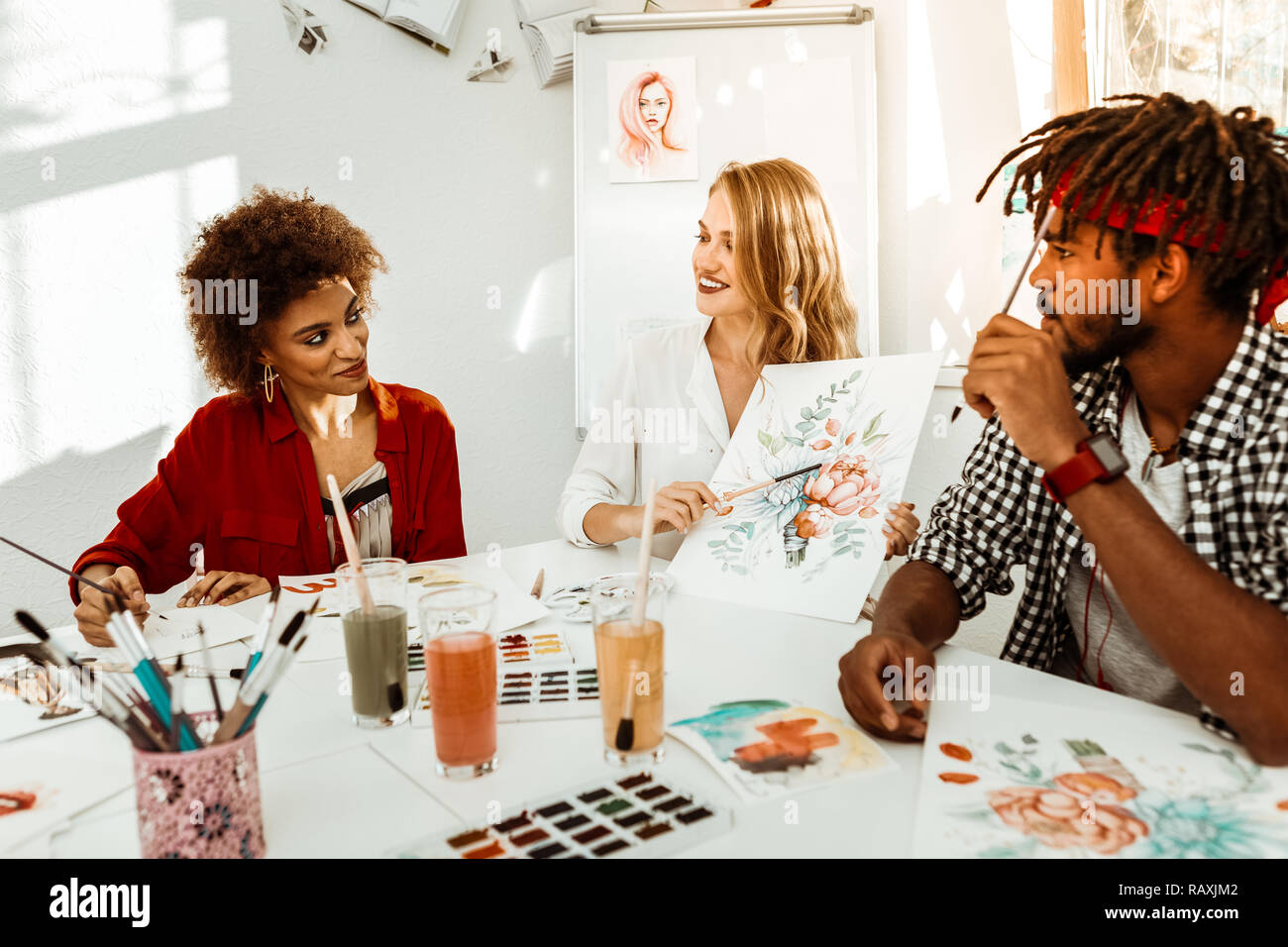 Talented blonde-haired art teacher sitting between her students Stock ...
