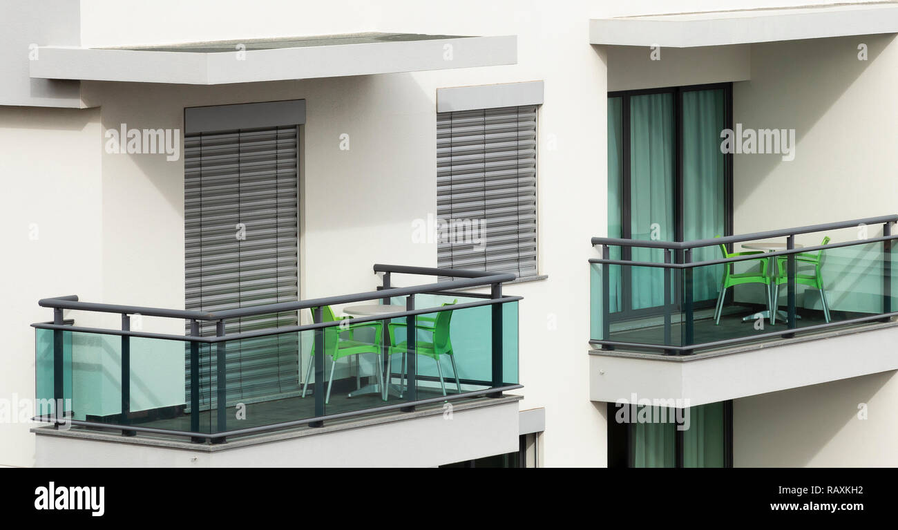 An image of a contemporary apartment exterior, with green chairs and grey balustrades and shutters. Shot in Madeira, Portugal. Stock Photo
