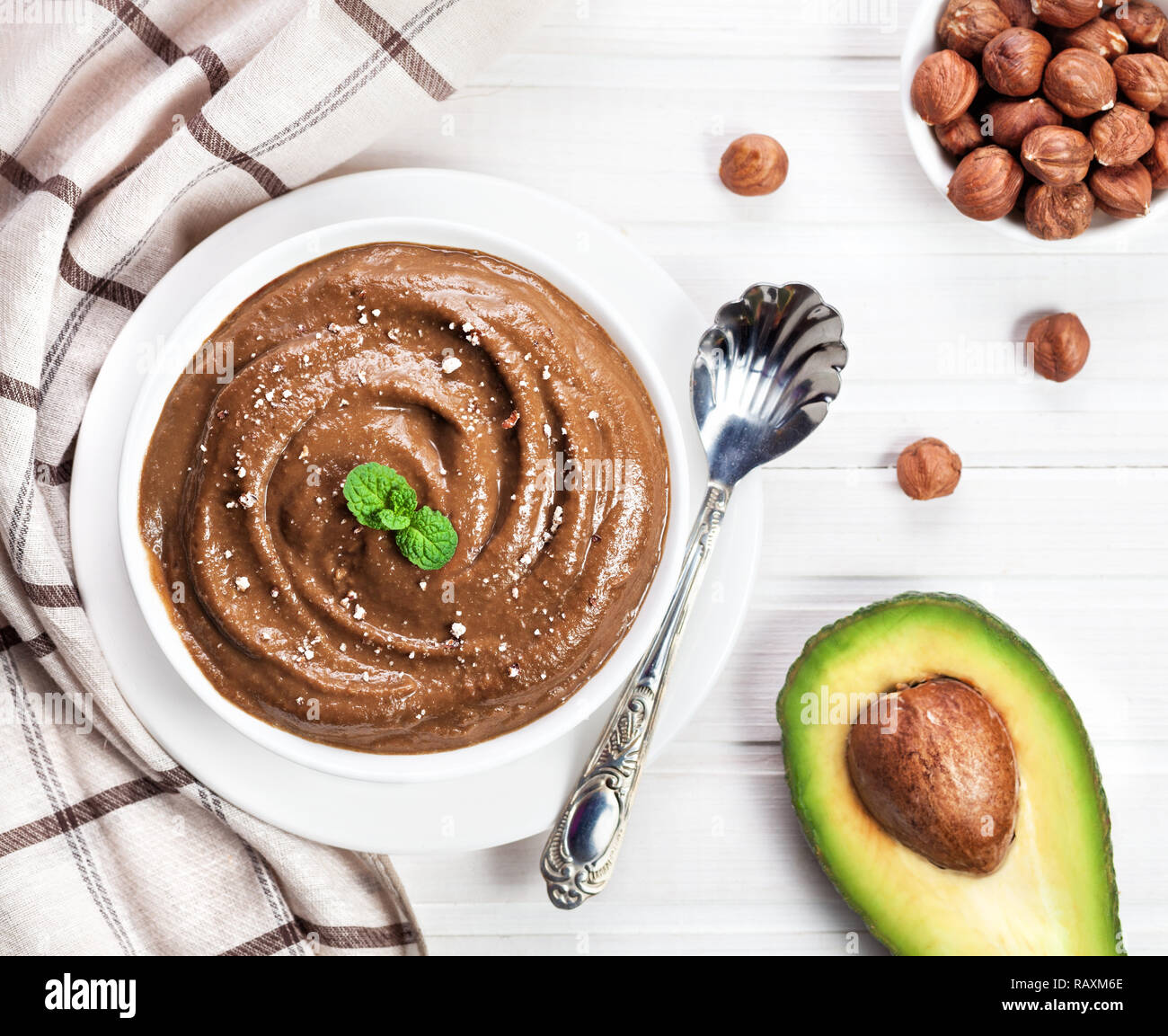 Vegan raw chocolate pudding from avocado, cocoa and hazel milk decorated with mint leaves and crushed nut on white wooden background Stock Photo