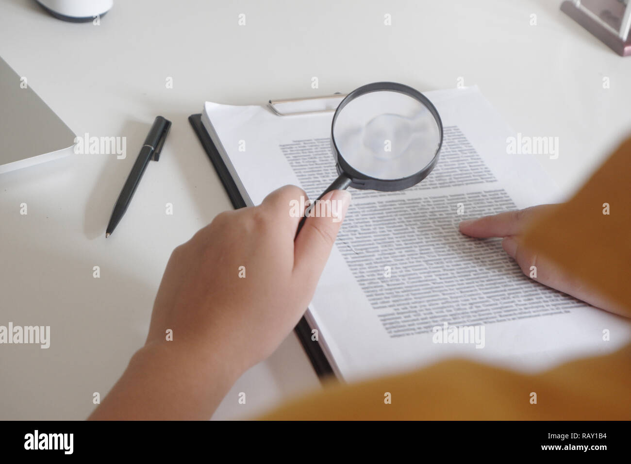 Businesswoman looking through a magnifying glass to documents note in the office Stock Photo