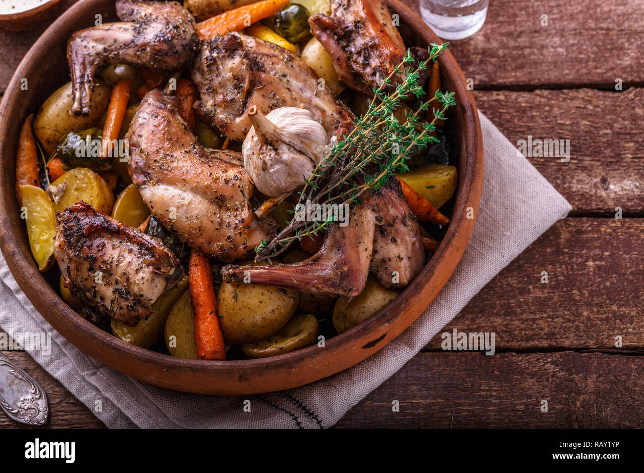 Oven baked rabbit with root vegetables and herbs, rustic style Stock
