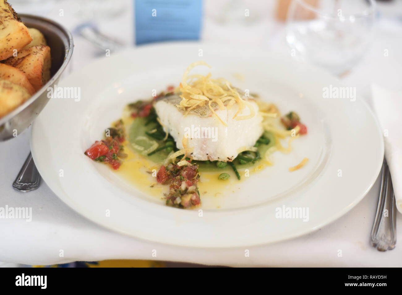 Fine dining fillet of fish main with sliced vegetable well presented a la carte meal in a table setting Stock Photo