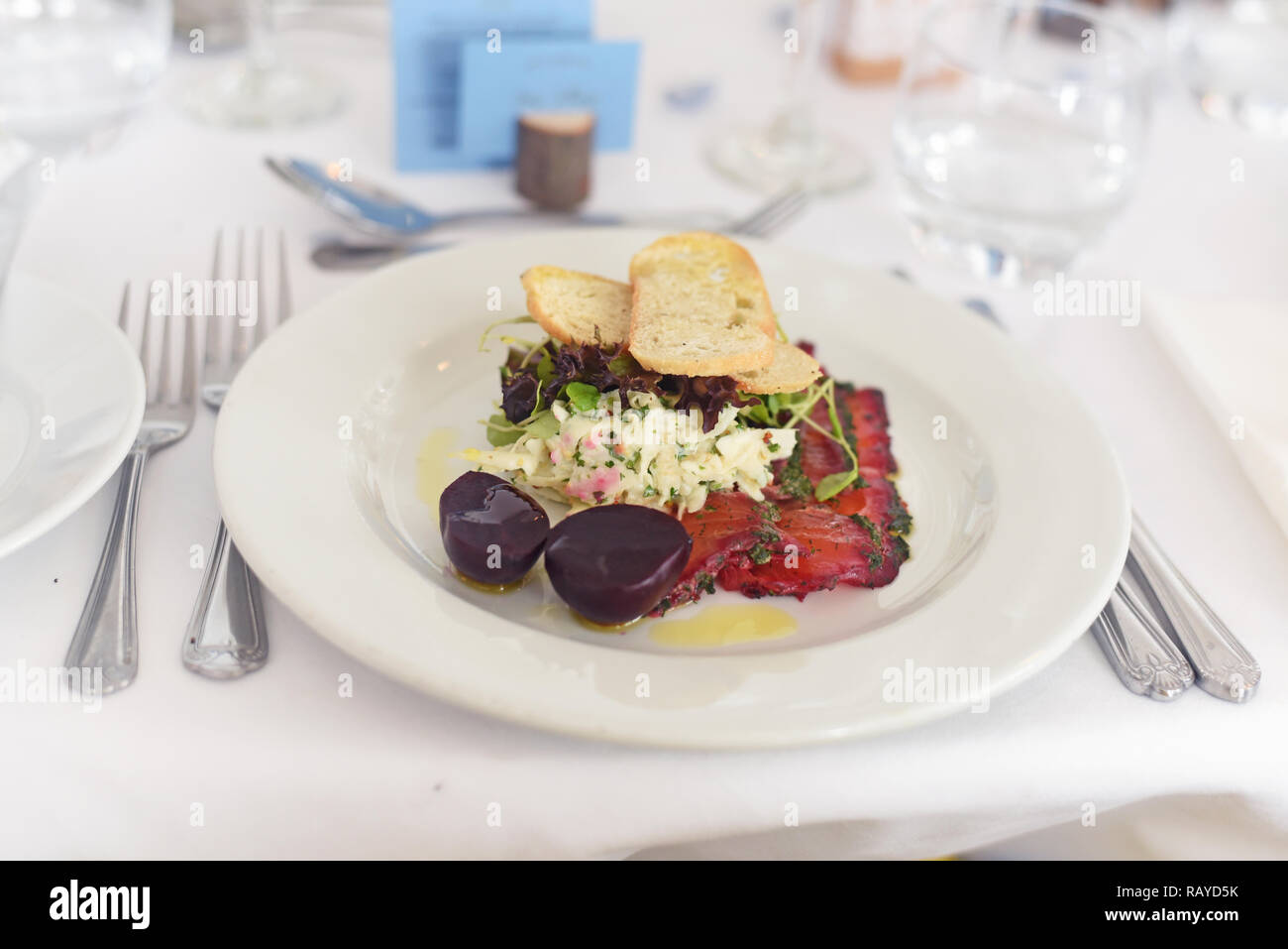 Fine dining smoked salmon starter with beetroot and salad well presented a la carte meal in a table setting Stock Photo