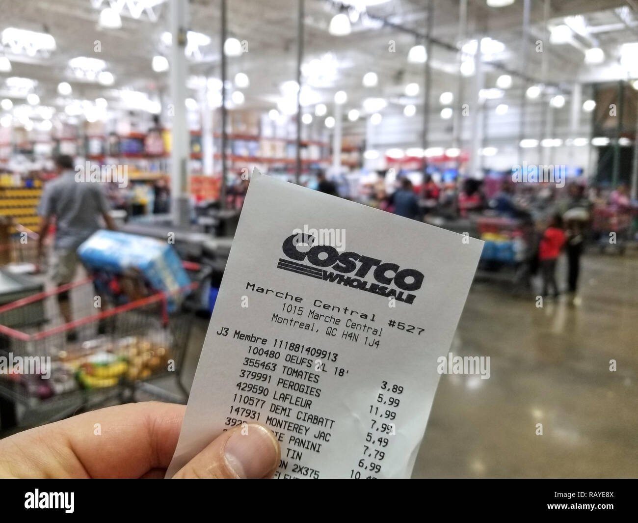 MONTREAL, CANADA - OCTOBER 5, 2018: A hand holding a receipt with the brand name and logo in Costco warehouse. Costco is an American corporation which Stock Photo