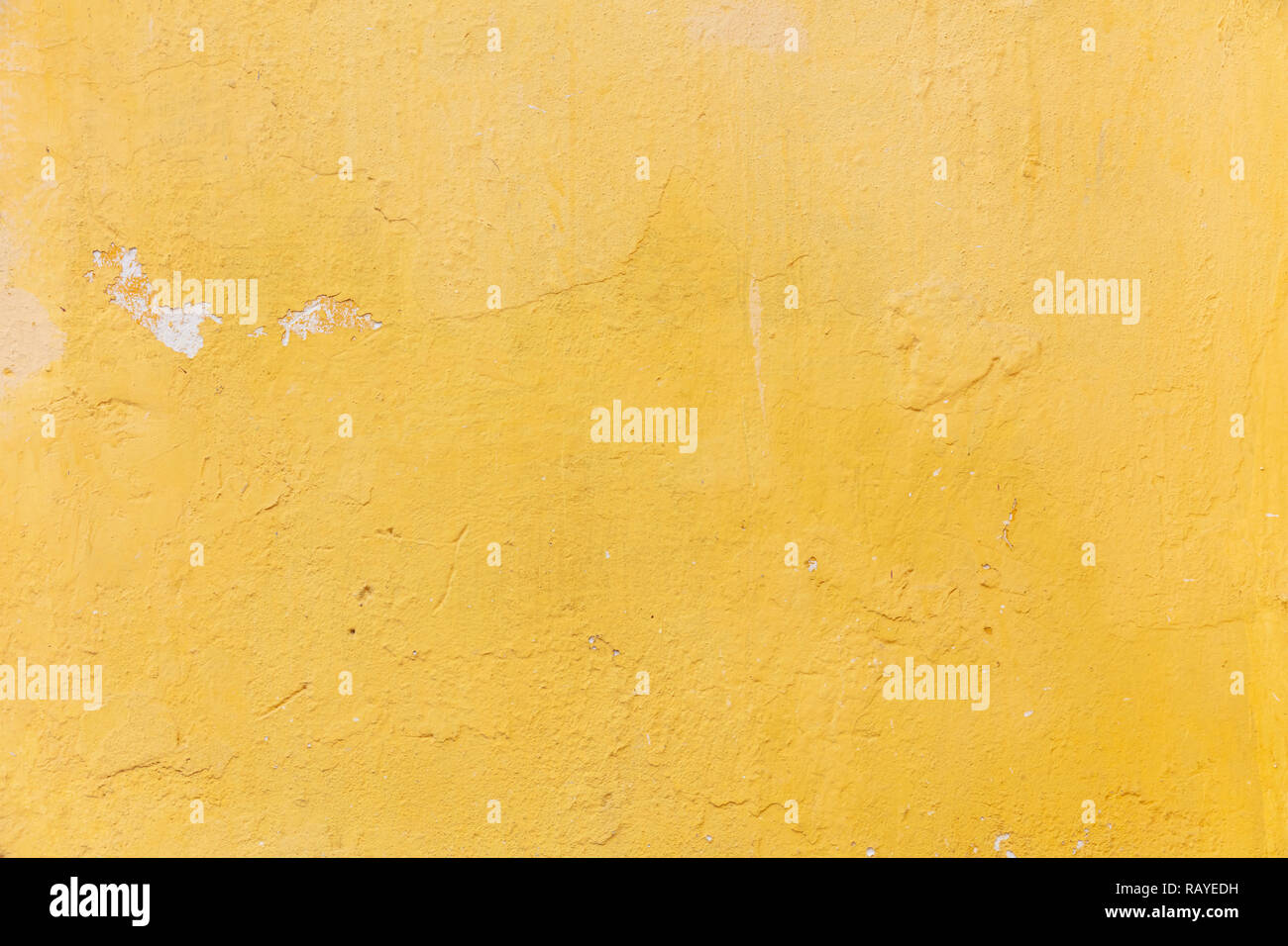 Bright yellow color, painted wall. Weathered and faded texture, grunge background. Exterior facade of a residential building Stock Photo
