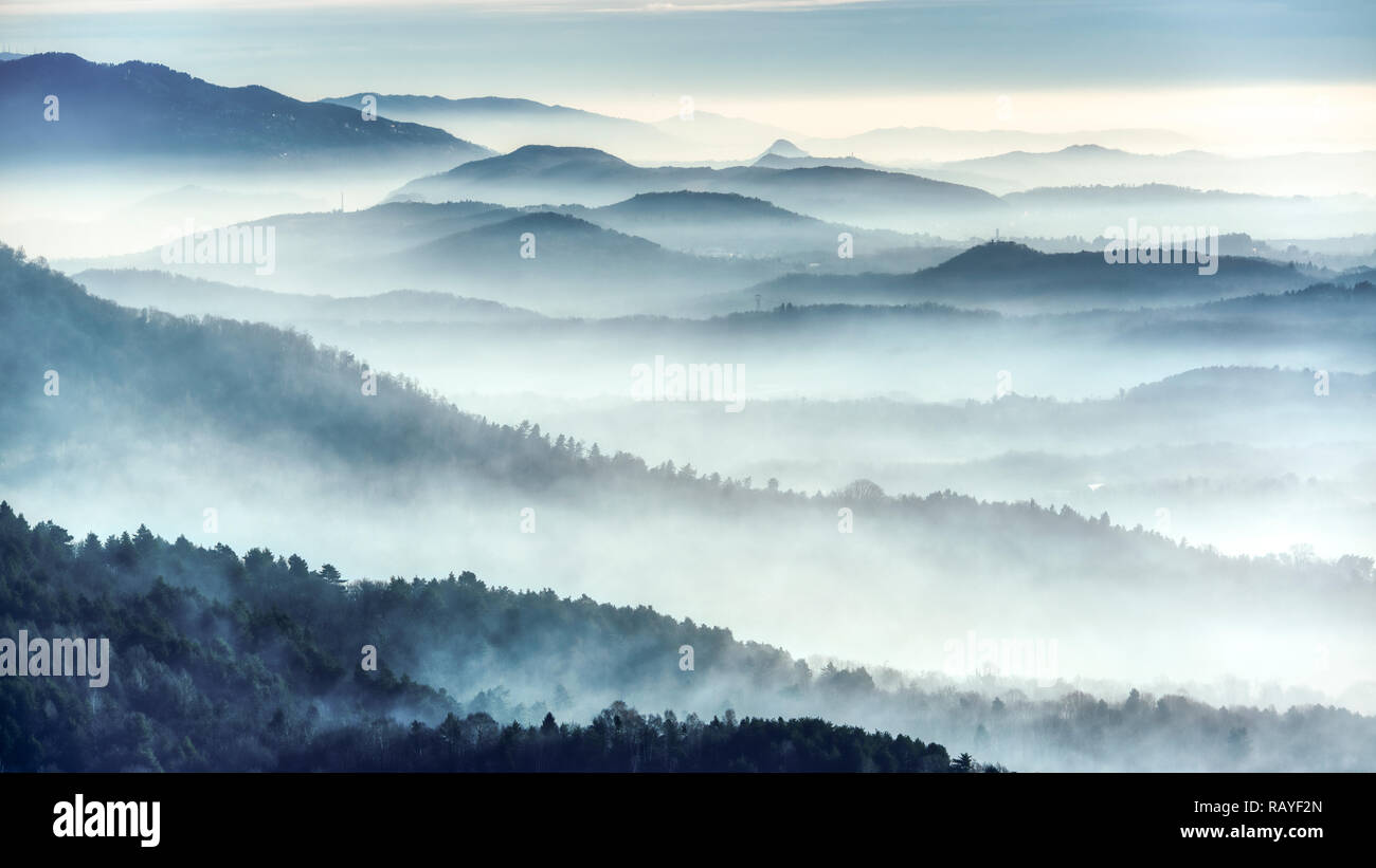 Foggy landscape on the hills in a winter cold morning seen from the mountains near the city of Varese Stock Photo