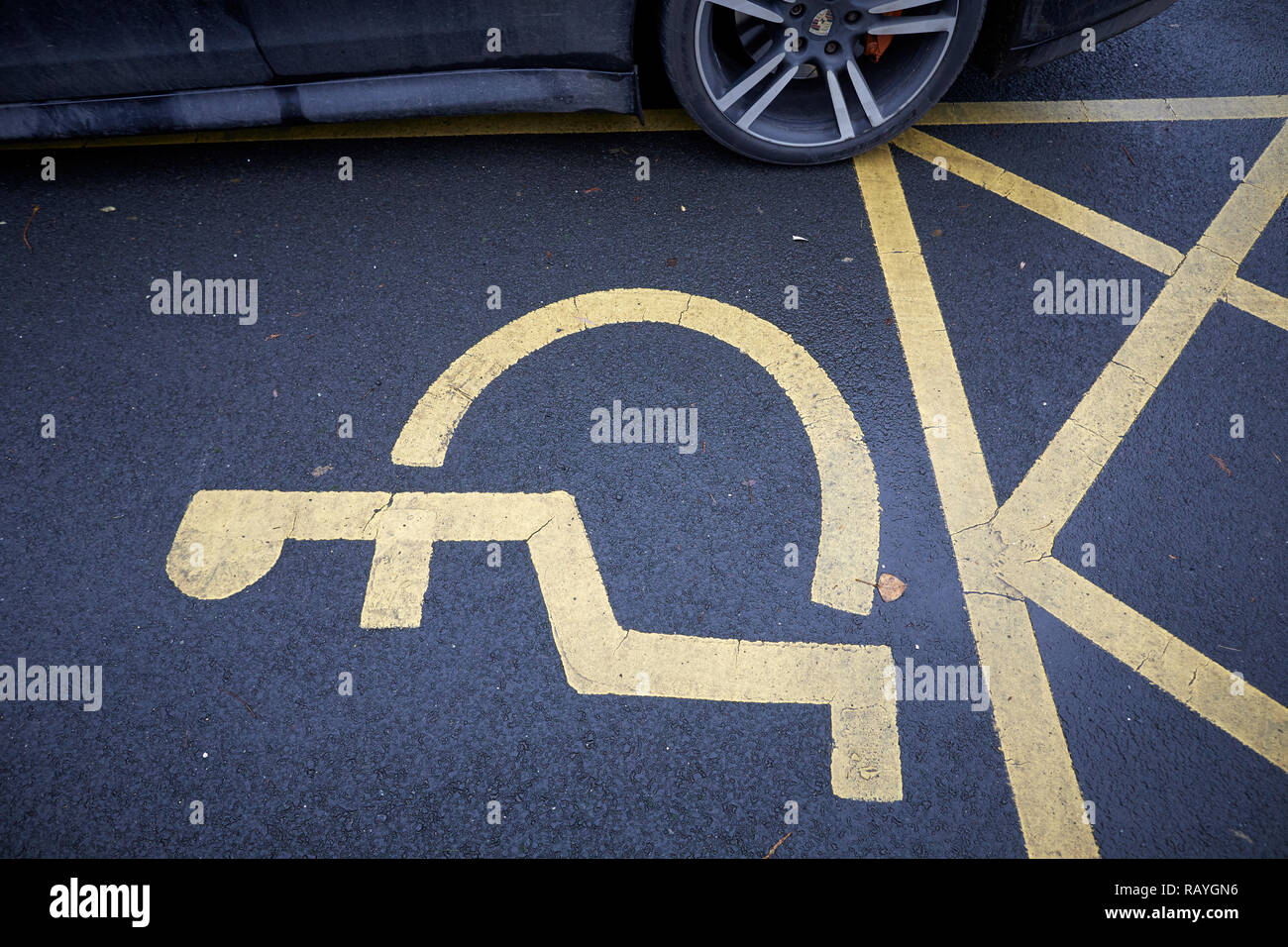 A car wheel parked badly encroaching on the space needed for disabled parking Stock Photo