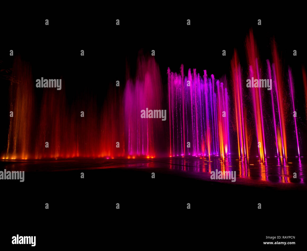 Large multi colored decorative dancing water jet led light fountain show at night Stock Photo