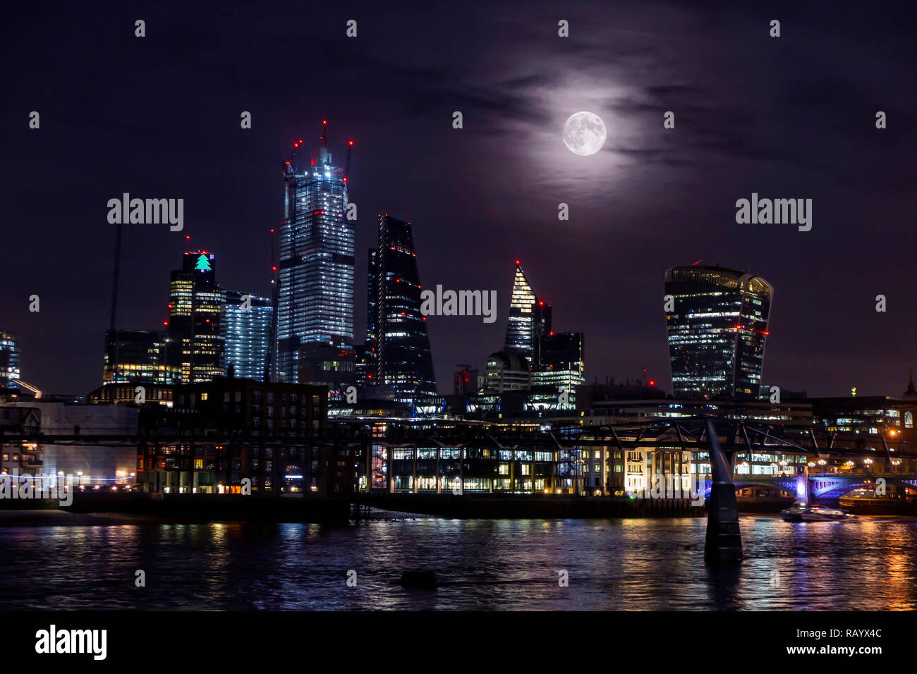 A very large moon rises from behind the towers of the City of London in an unusual display Stock Photo