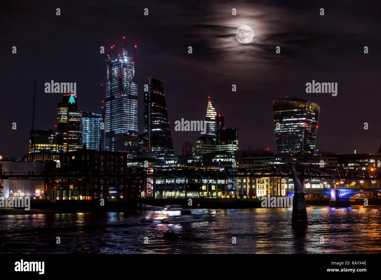 A very large moon rises from behind the towers of the City of London in an unusual display Stock Photo
