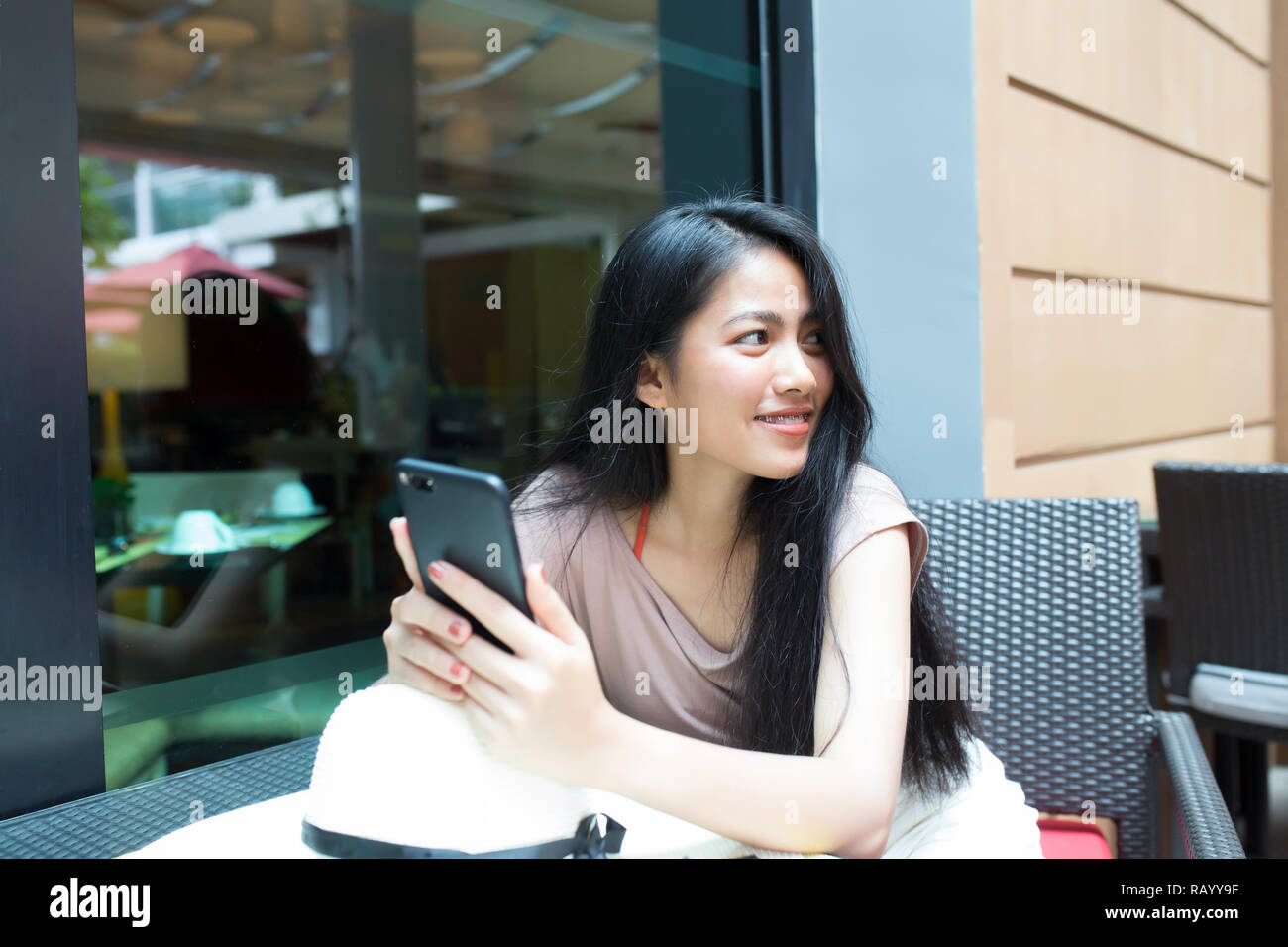 Pretty asian woman relaxing in the coffee shop and holding smart phone ...
