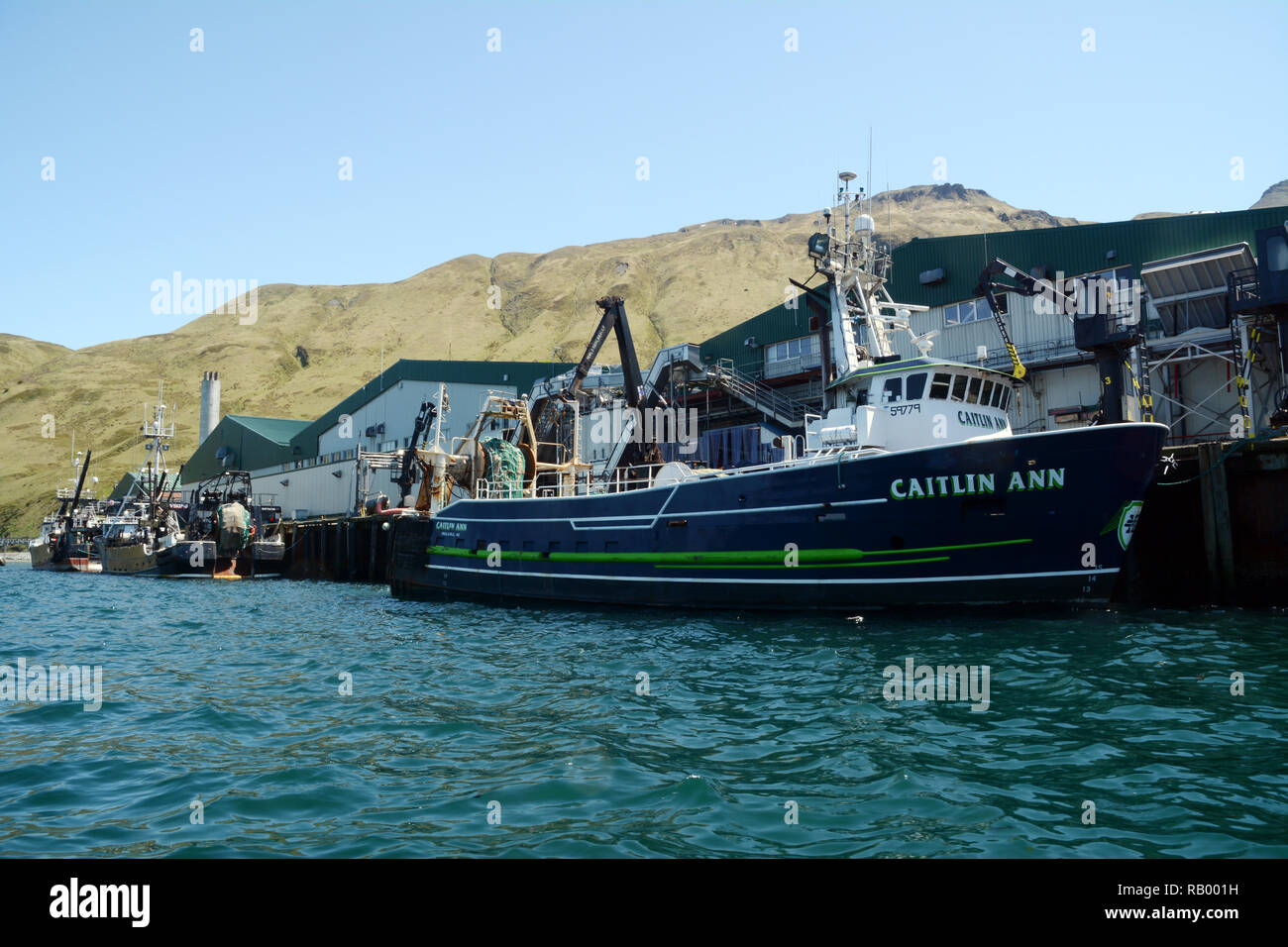 A commercial fishing boat unloads its cargo of fresh fish at a seafood processing plant in Dutch Harbor, Unalaska Island, Alaska, United States. Stock Photo