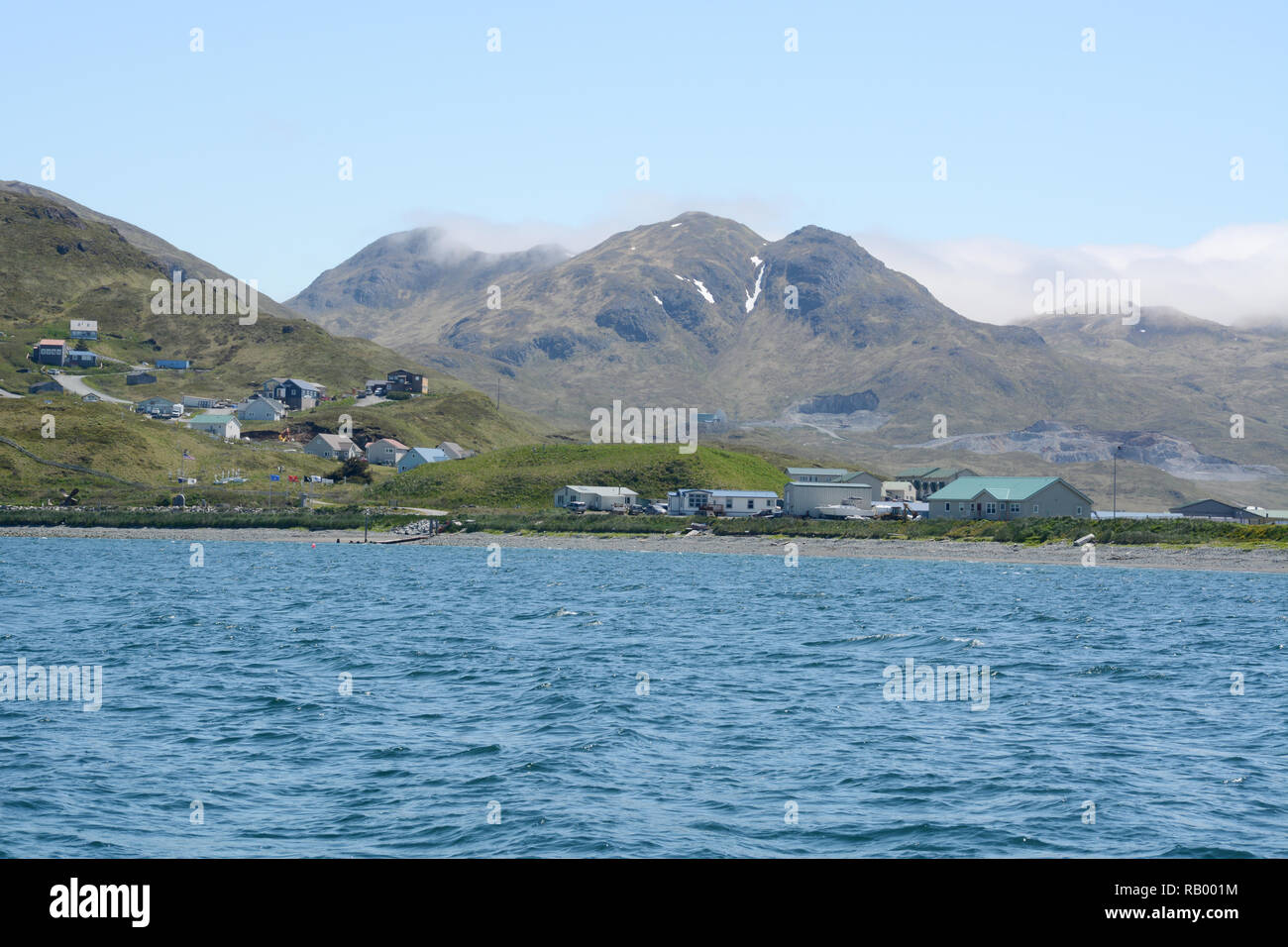 Homes on the edge of Unalaska, also known as Dutch Harbor, surrounded by mountains and the Bering Sea, Unalaska Island, Aleutian archipelago, Alaska. Stock Photo