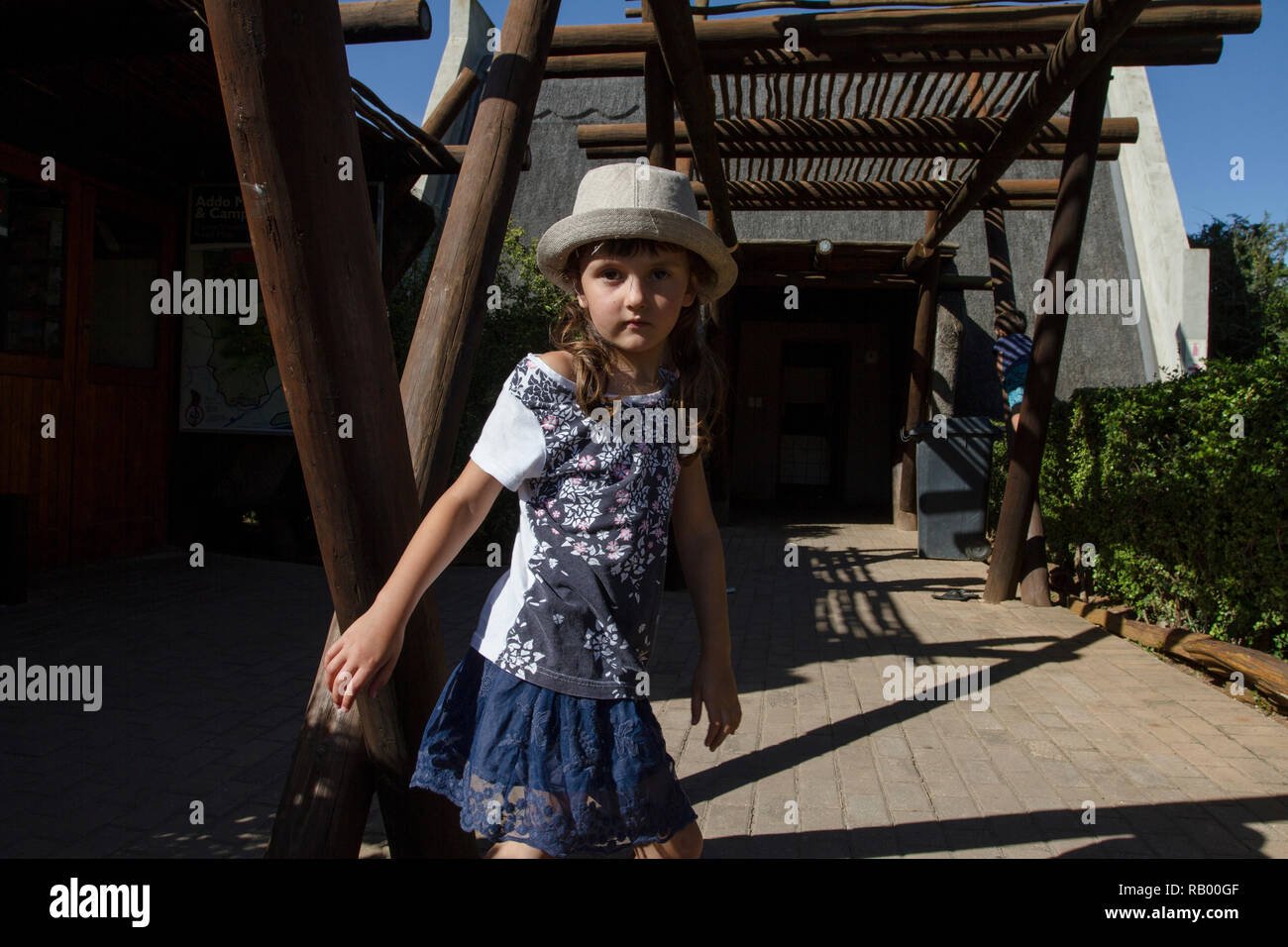 Five year old girl, wearing a hat, plays outside the entrance to the Addo Elephant National Park, Eastern Cape, South Africa Stock Photo