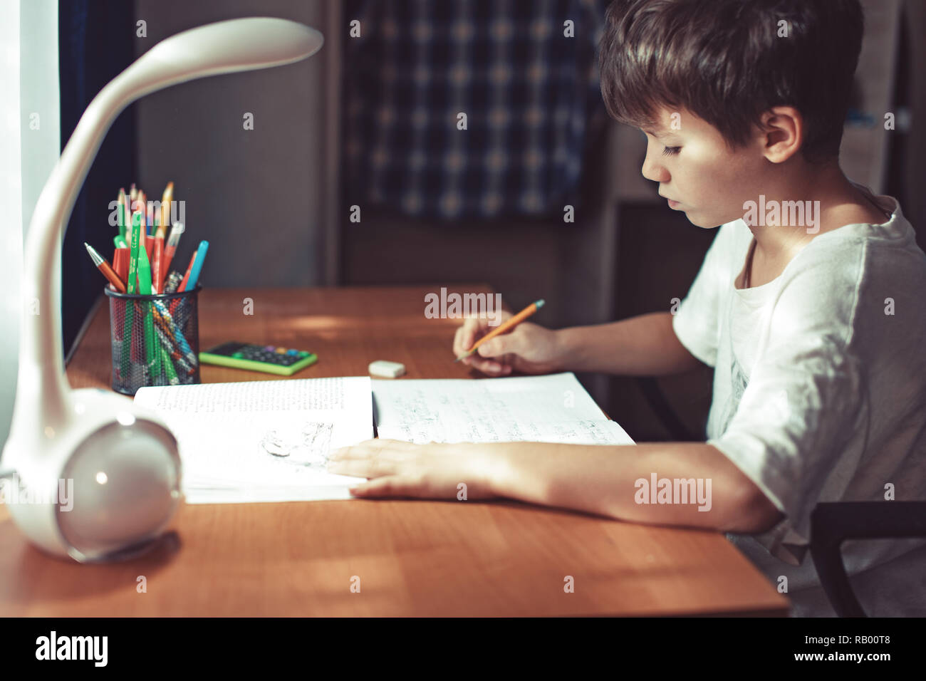 Young little schoolboy doing homework or learning at home Stock Photo