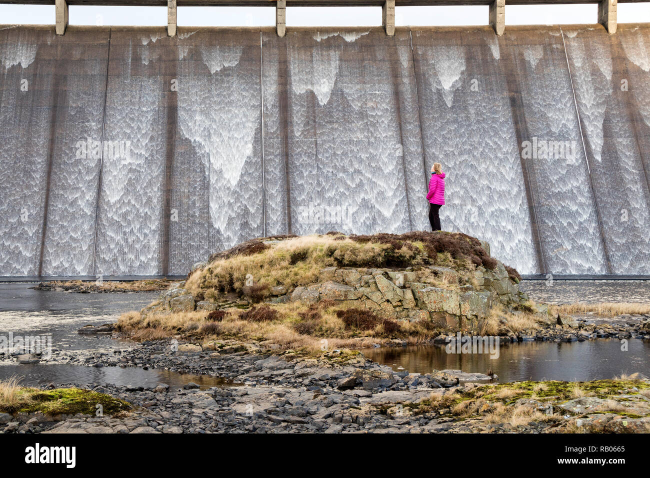 Teesdale, County Durham, UK.  Saturday 5th January 2019.  UK Weather.  After a dry summer in Northern England a walker enjoys the spectacle of water cascading over the overflow of a brim full Cow Green reservoir in Teesdale, County Durham. Credit: David Forster/Alamy Live News Stock Photo
