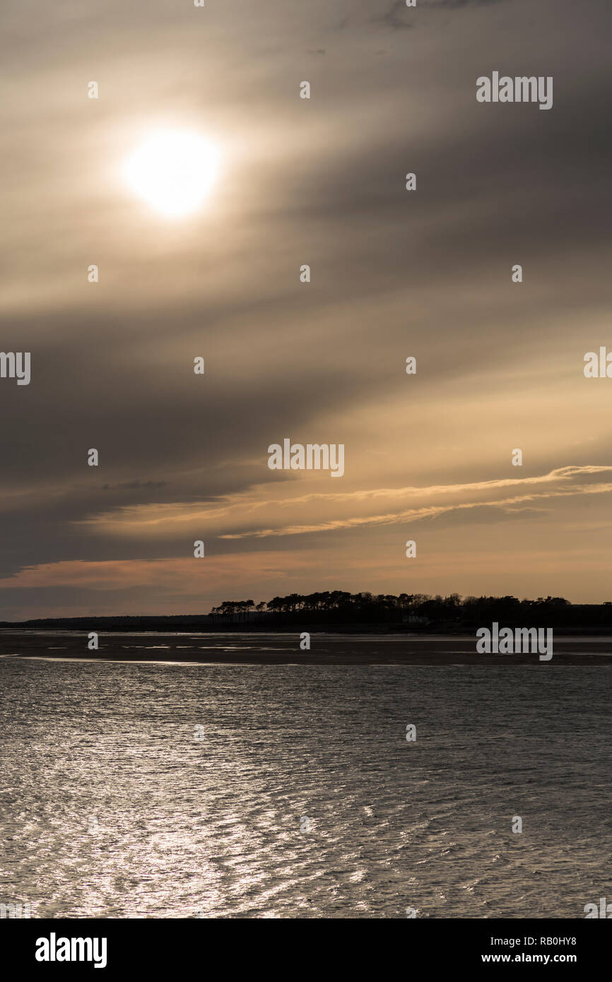 Sun behind clouds over the North Wales coast at Caernarfon Stock Photo