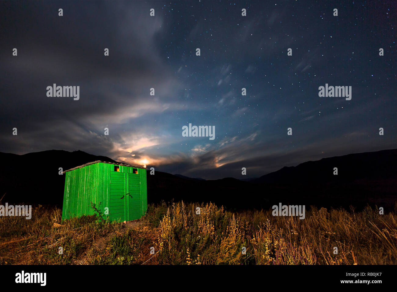 Green wooden hut with moon setting and stars in the sky, in Kolsai Lakes area, Kazakhstan. Stock Photo