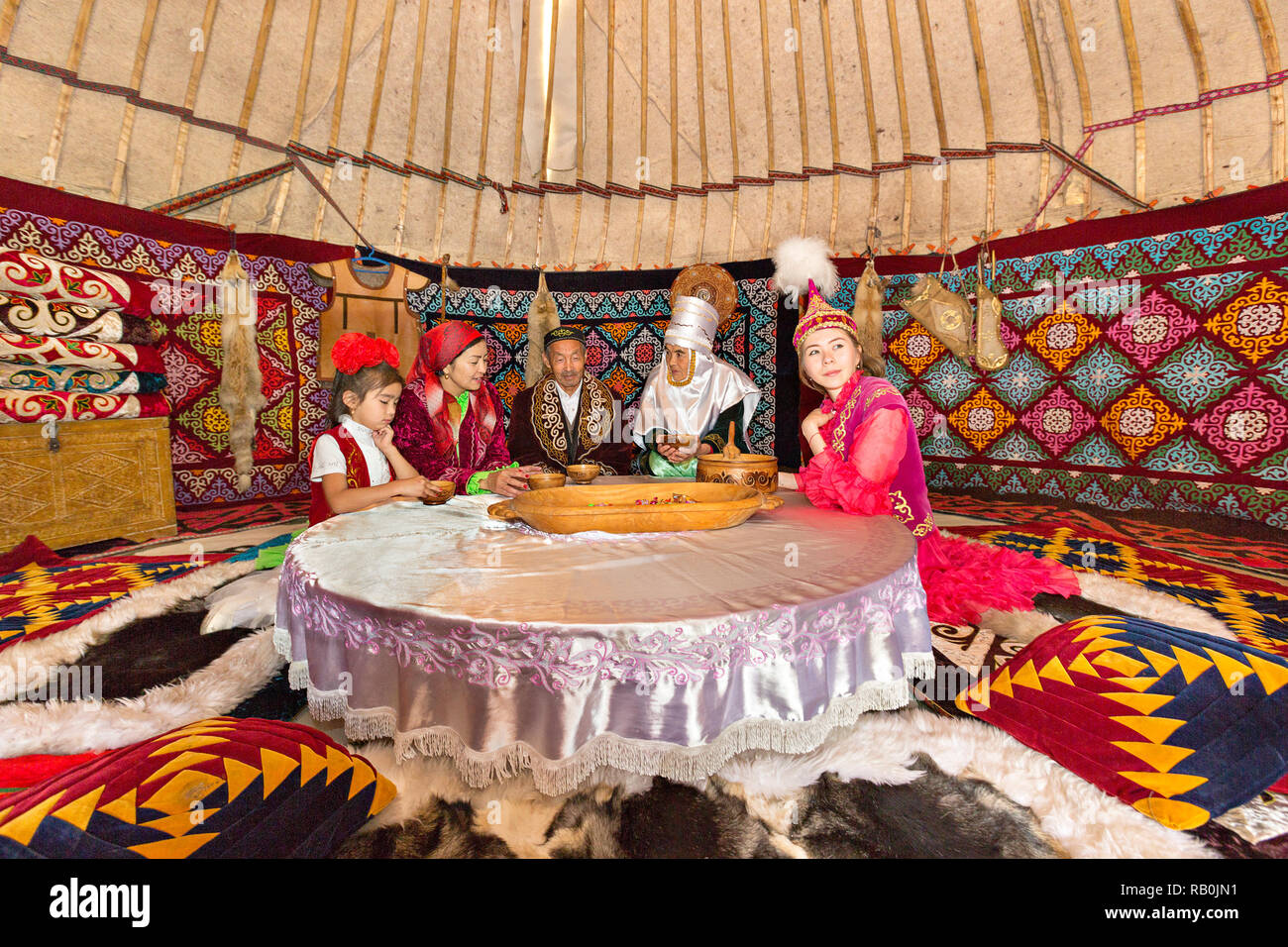 Kazakh people in traditional costumes in a nomadic tent known as yurt, in Kazakhstan. Stock Photo