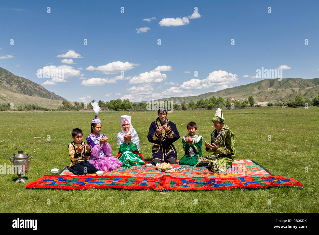 Kazakh family praying all together before they start having their picnic lunch in Saty Village, Kazakhstan. Stock Photo