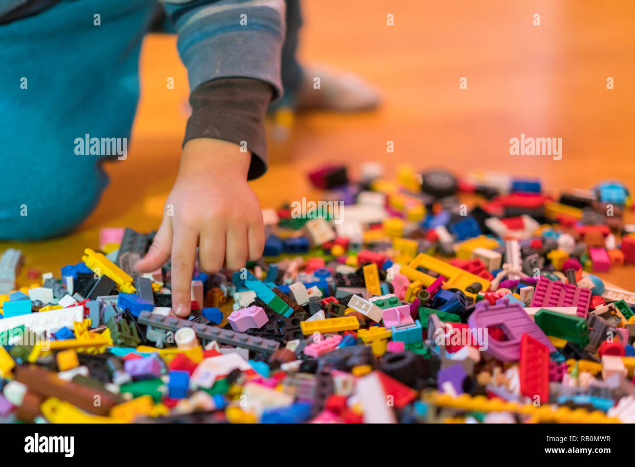 Close up of colorful plastic bricks on the floor. Early learning. Children's plastic constructor on the floor. Children's hands play a little construc Stock Photo