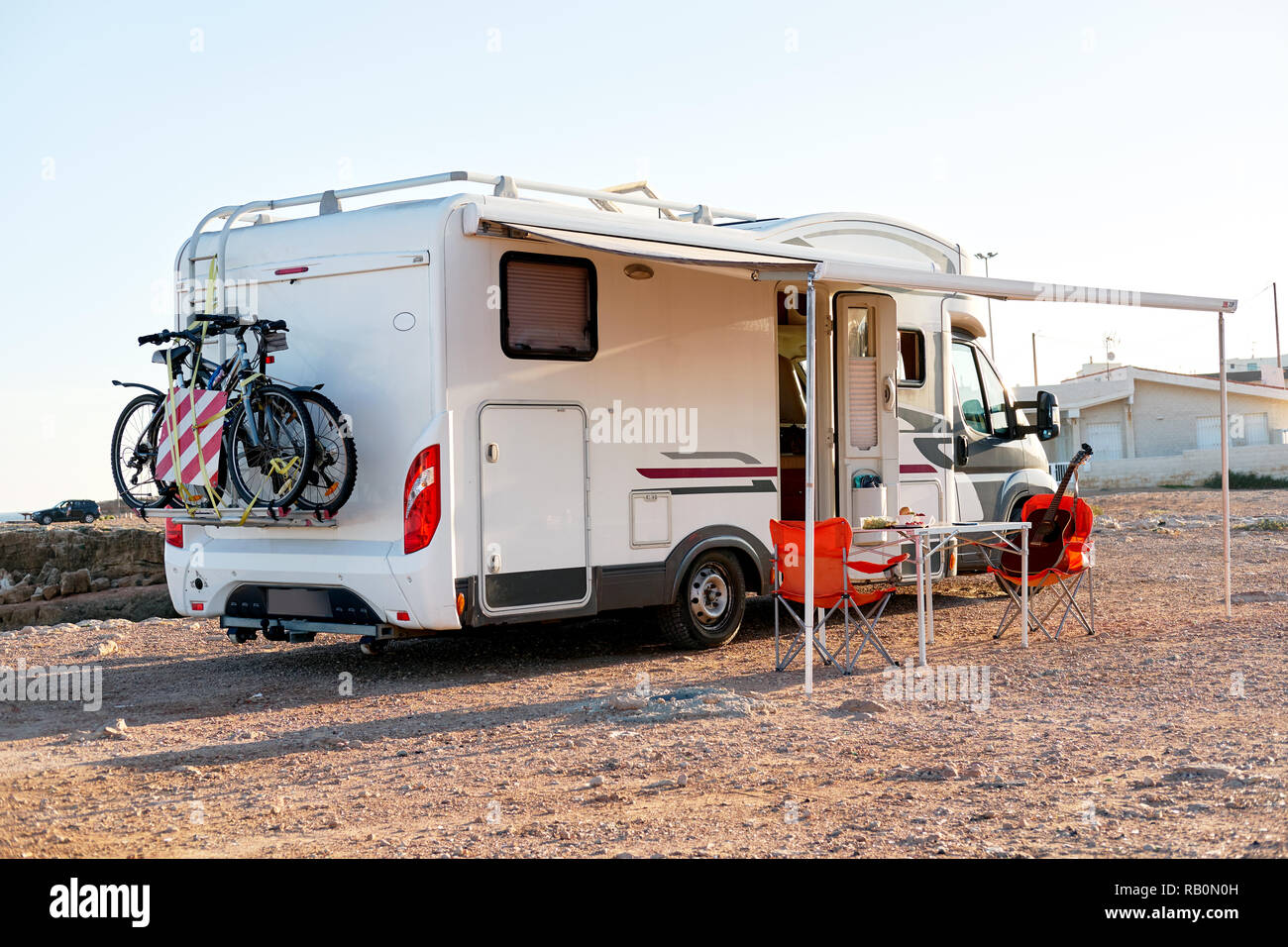 Empty folding chairs and table under canopy near recreational vehicle camper trailer. Adventure journey, active people traveling by motor home concept Stock Photo