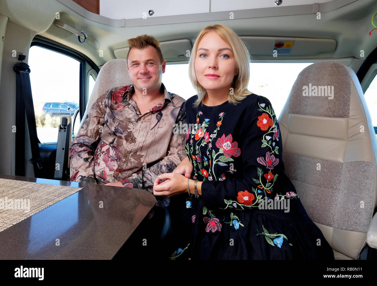 Married middle age couple sitting inside of recreational vehicle looking at camera. Active people lifestyle, adventure and journey Stock Photo