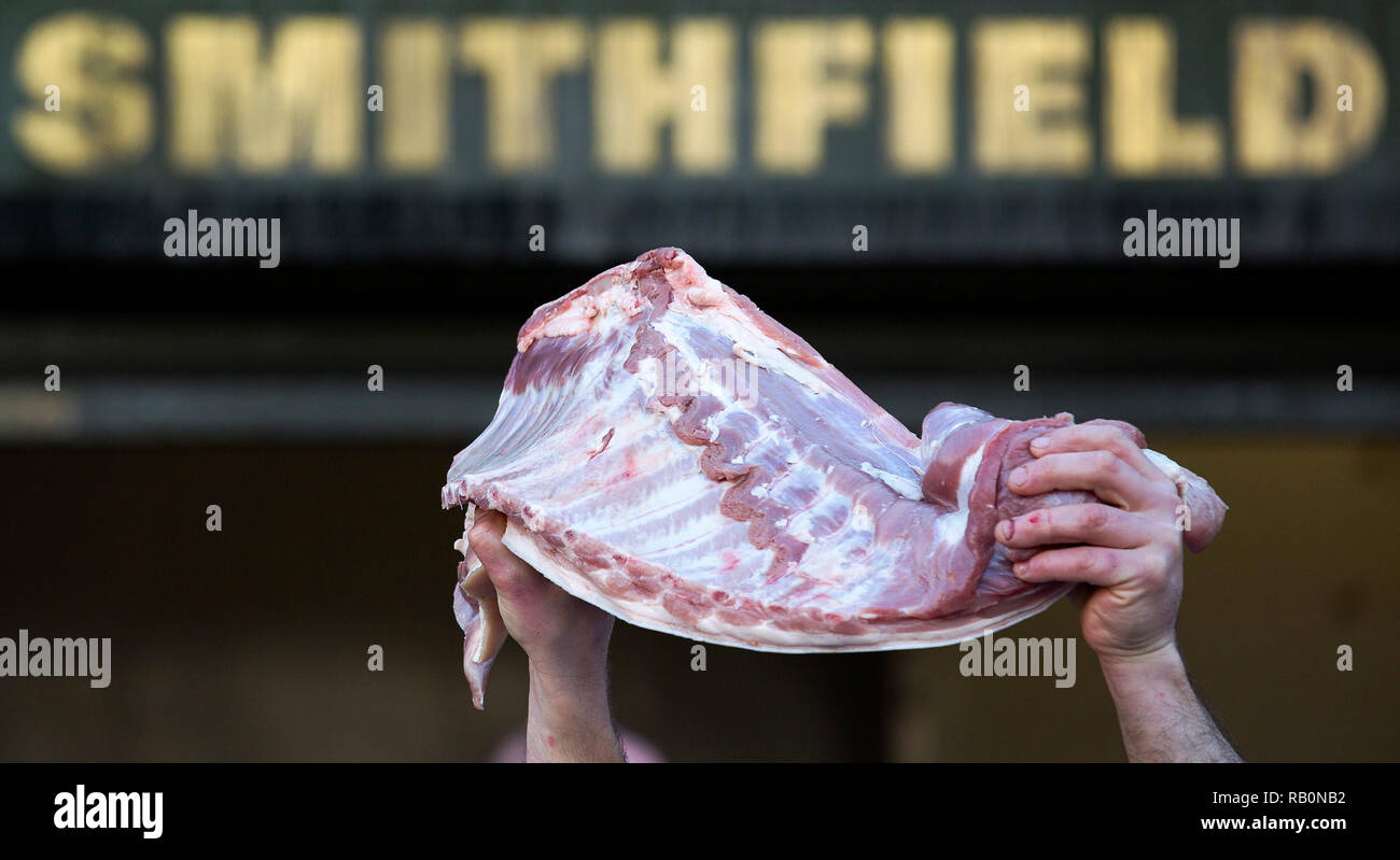 A butcher holds meat to sell during the annual Christmas Eve auction at Smithfield Market in the City of London on December 24, 2014. Stock Photo