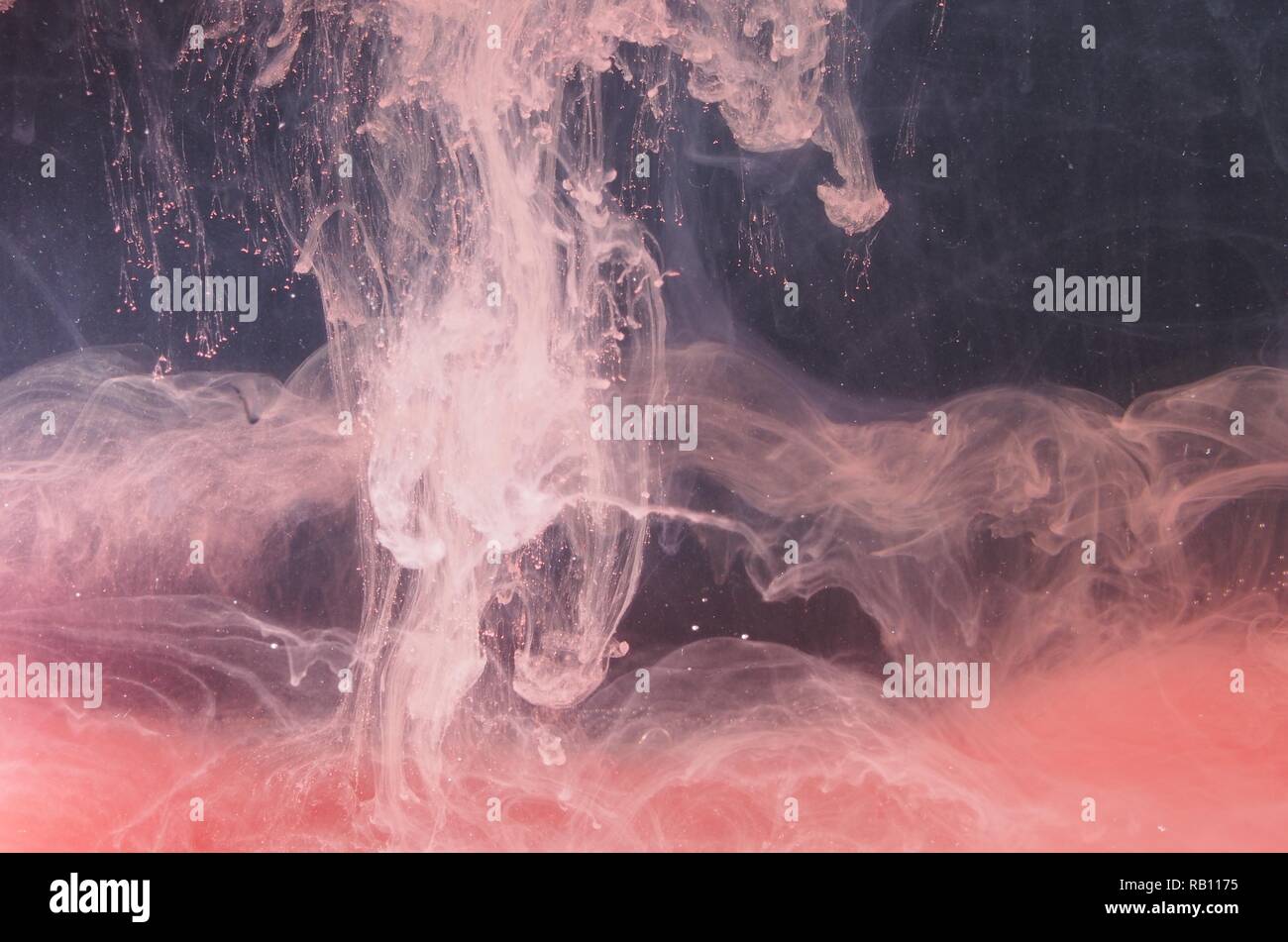 A drop of paint dissolves in water. Red paint is mixed with water. An