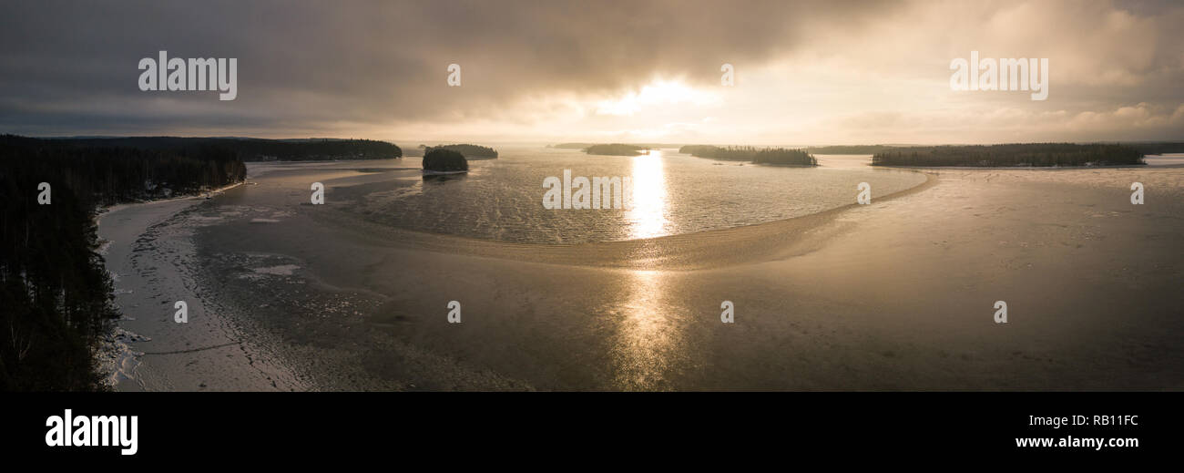 Aerial panorama of a partly frozen lake during sunset. Stock Photo