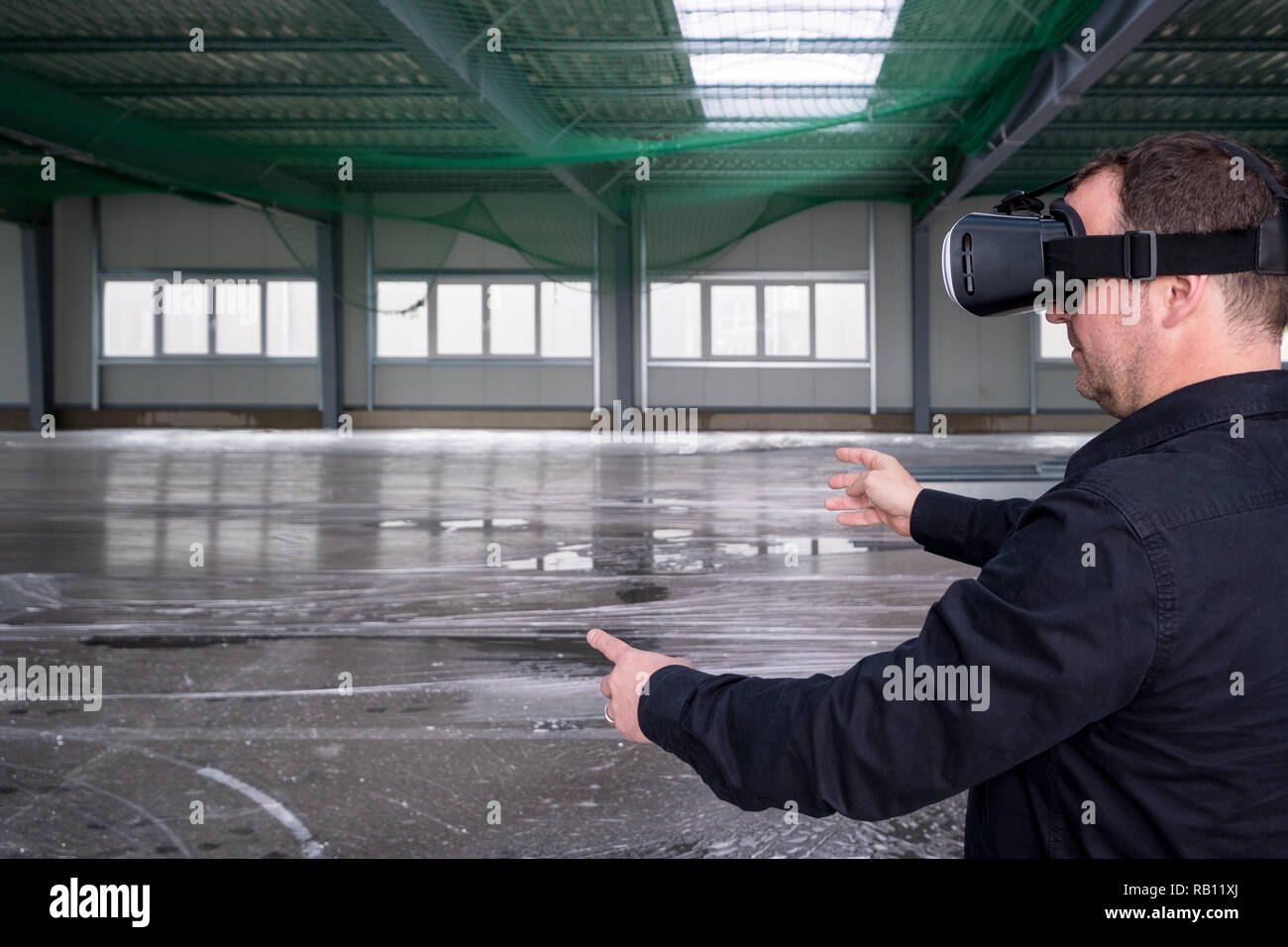 Construction worker standing at indoor construction site wearing vr eyeglasses or goggles, with space for your copytext or imagery projection Stock Photo