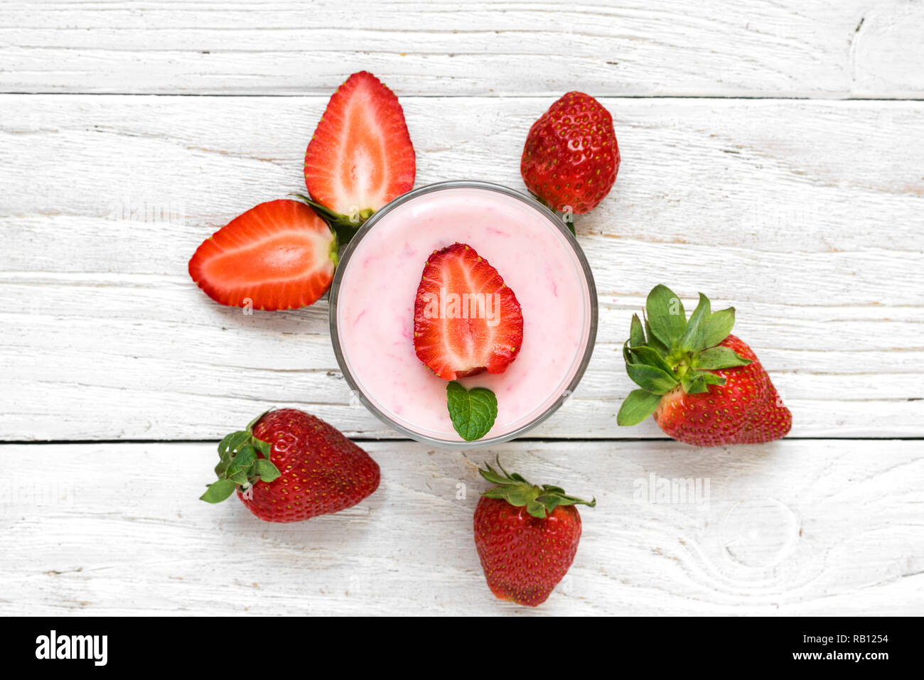 strawberry yogurt in a glass with fresh berries on white wooden background. healthy breakfast. top view Stock Photo