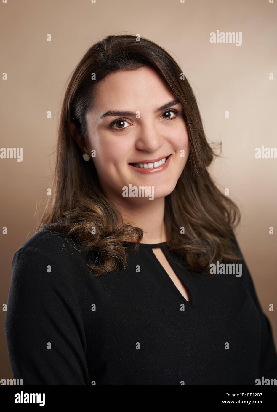 Portrait of young smiling woman on brown studio background Stock Photo