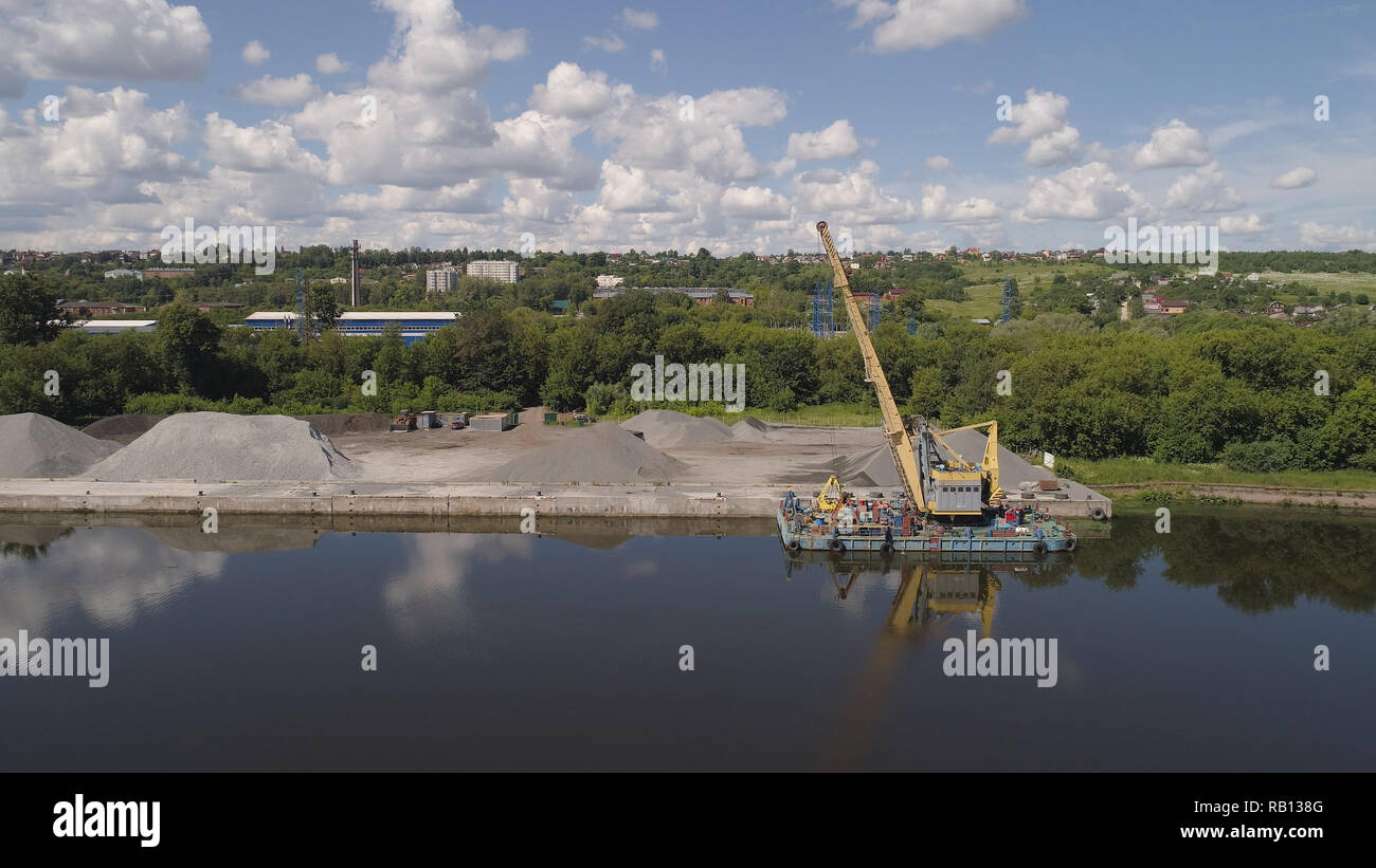 Aerial view large crane an excavator mounted on barge. Excavator on river for unloading and loading sand and rubble. Stock Photo