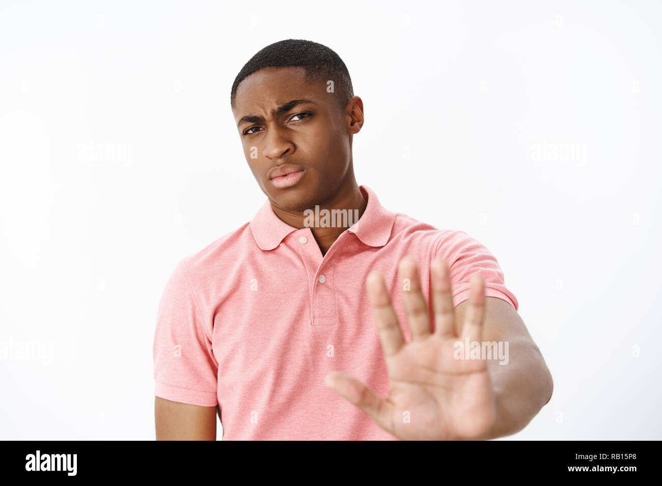No bro thanks. Serious-looking displeased strict african american masculine guy pulling hand forward in stop and rejection gesture frowning being displeased with offer refusing over gray background Stock Photo
