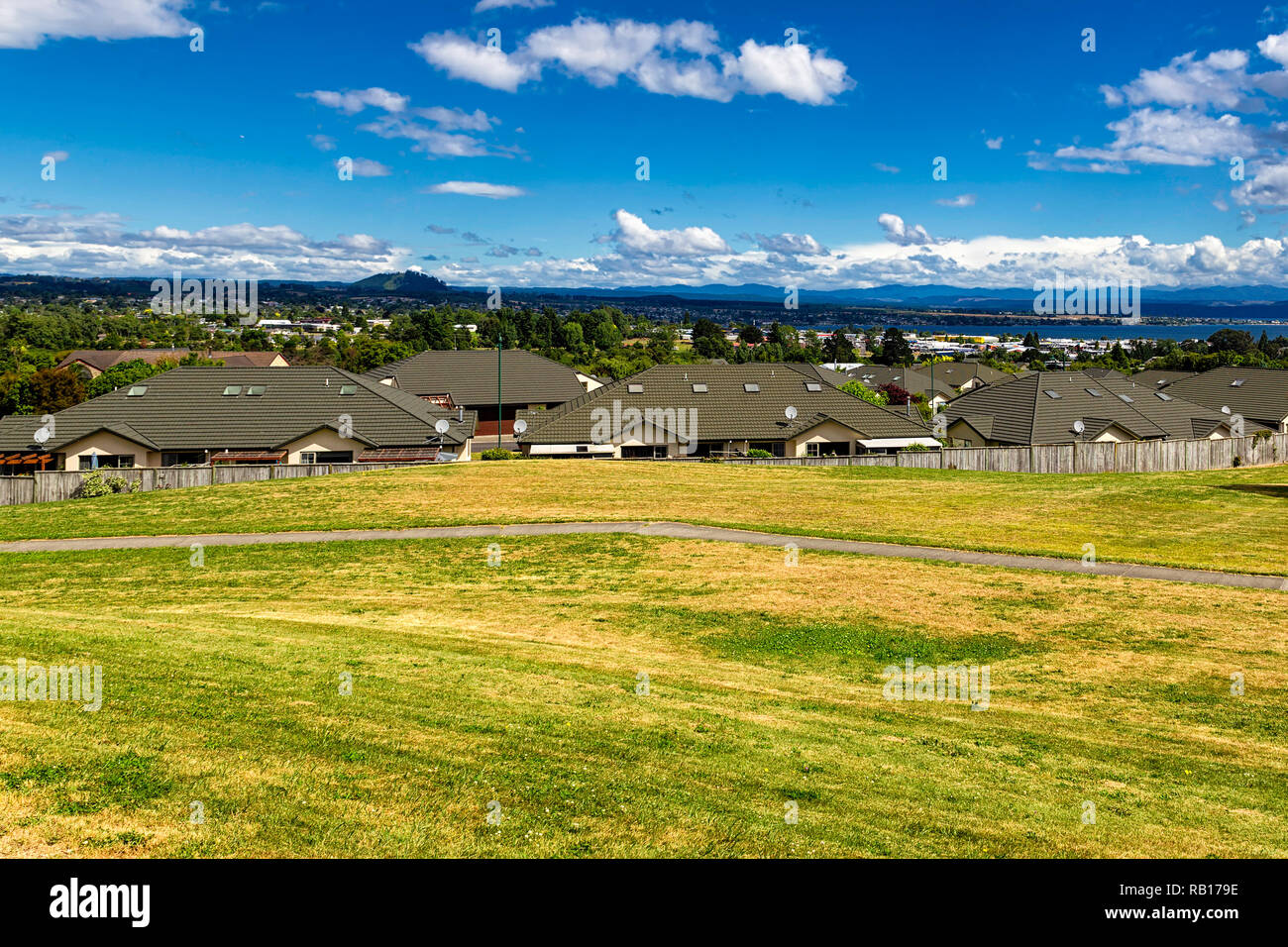 Green and yellow grass lawn, roofs of the houses and the view of Taupo town in New Zealand Stock Photo